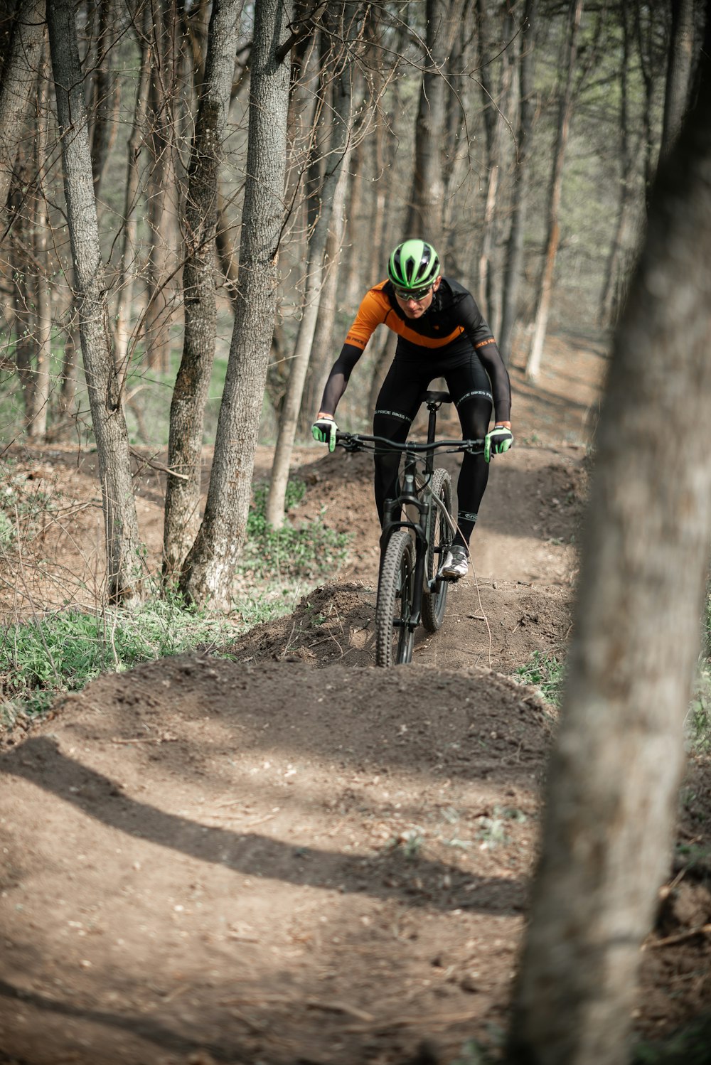 man in black and red jacket riding black mountain bike on brown dirt road during daytime