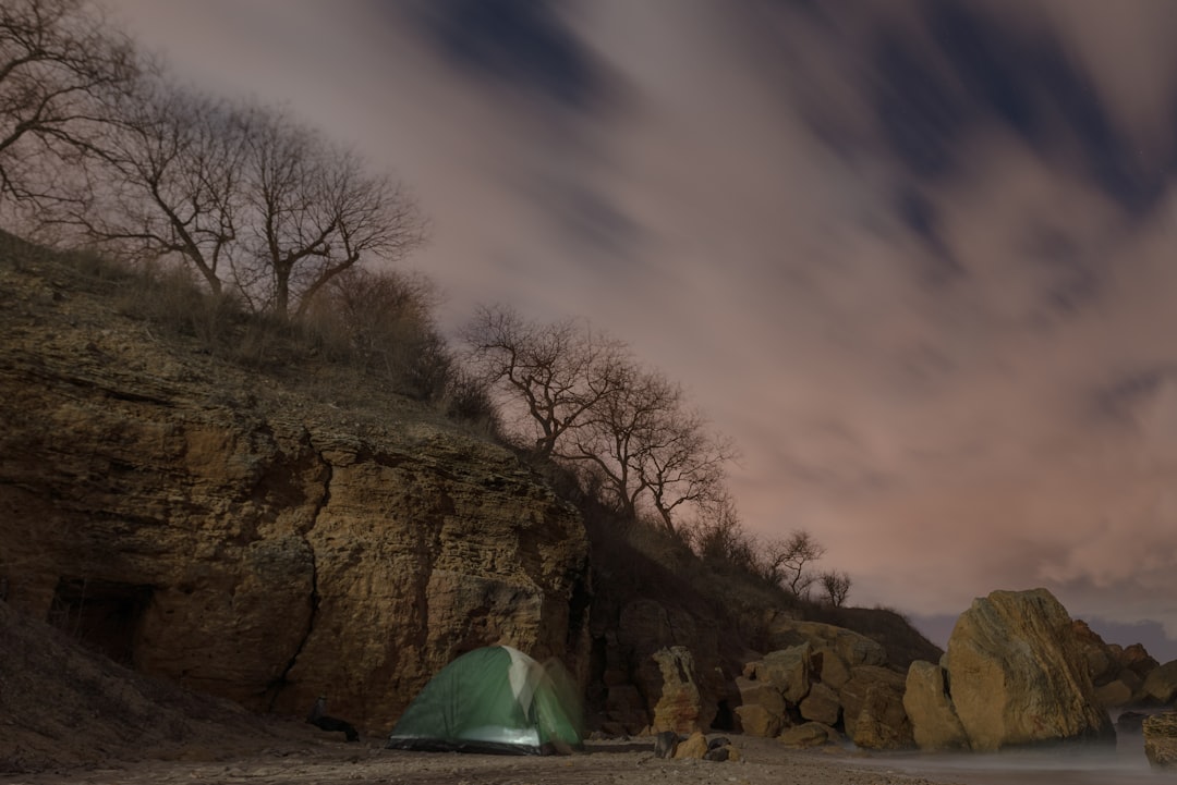 green tent on brown rock formation under blue sky