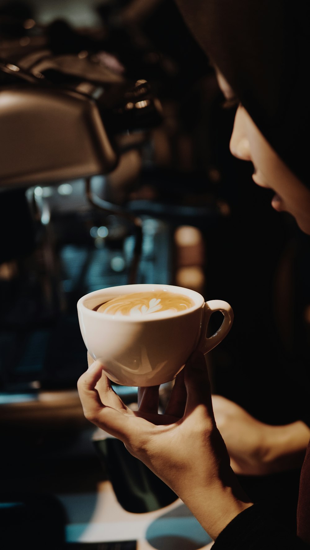 person holding white ceramic cup with brown liquid