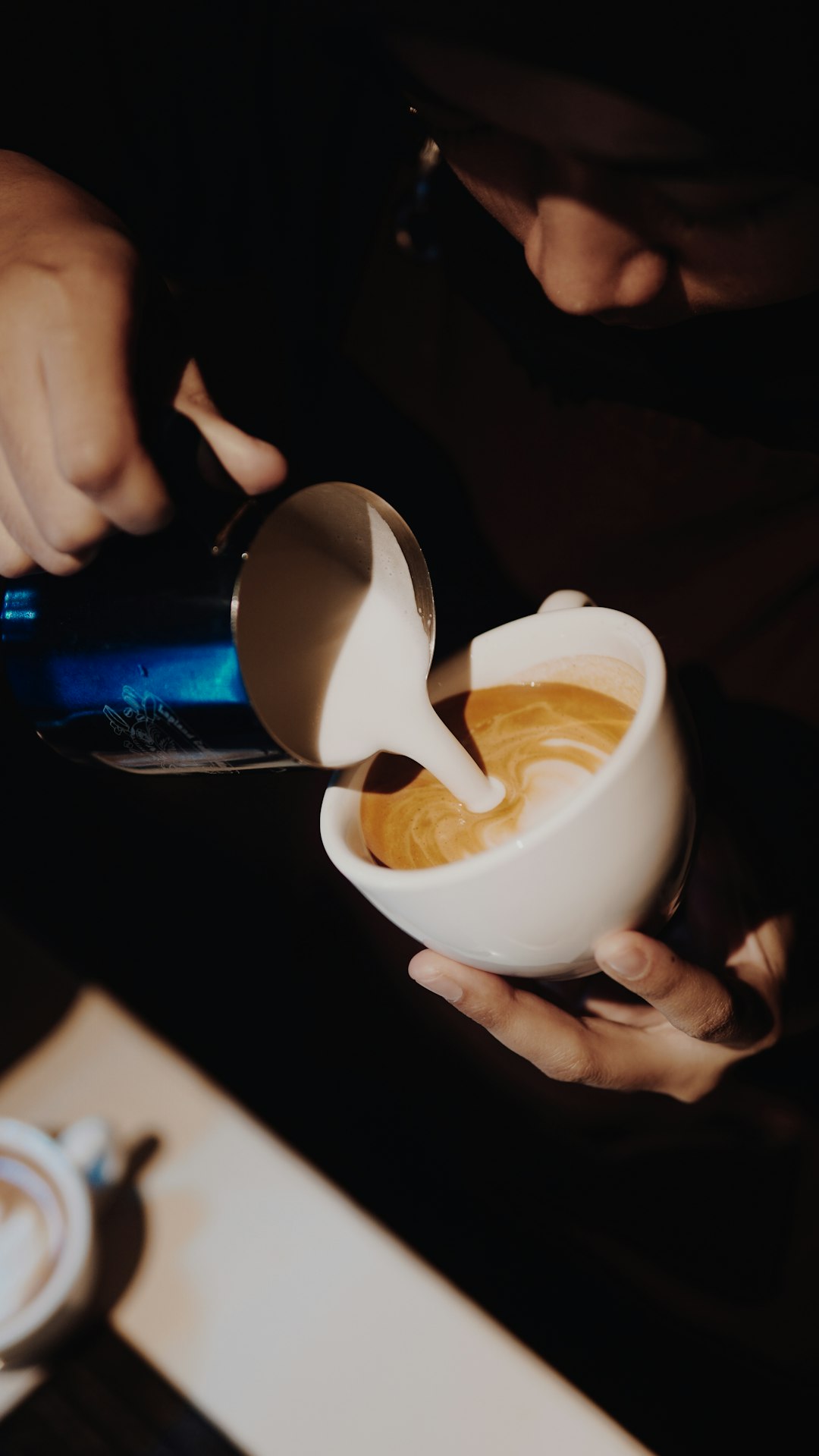 person pouring white liquid on white ceramic cup