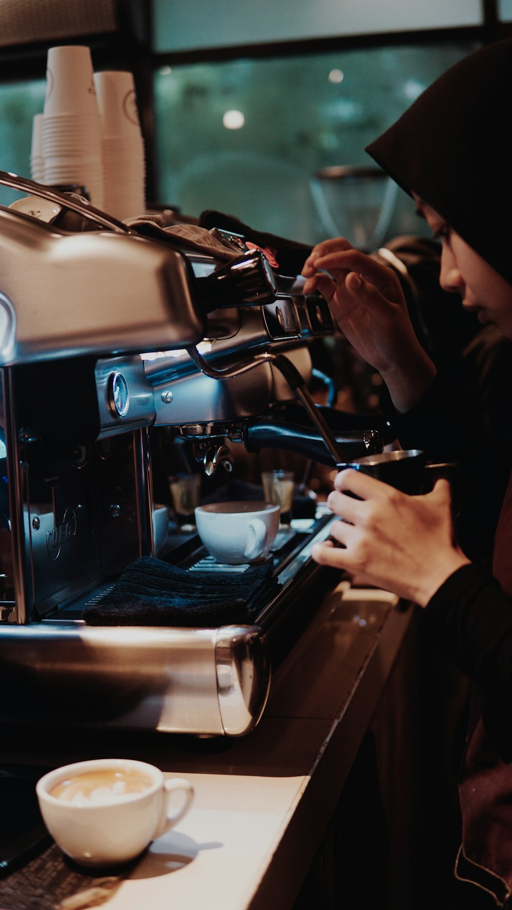 man in black jacket pouring coffee on white ceramic teacup