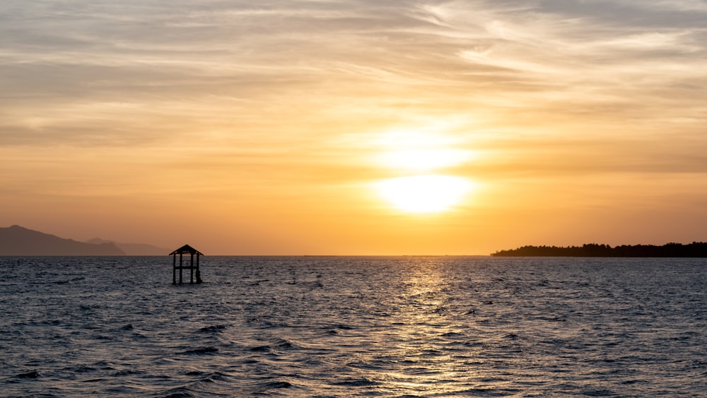 silhouette of house on sea during sunset