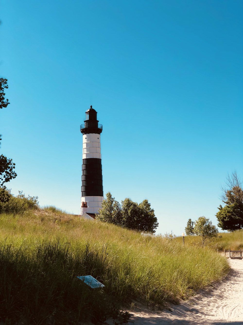 white and black lighthouse on green grass field under blue sky during daytime