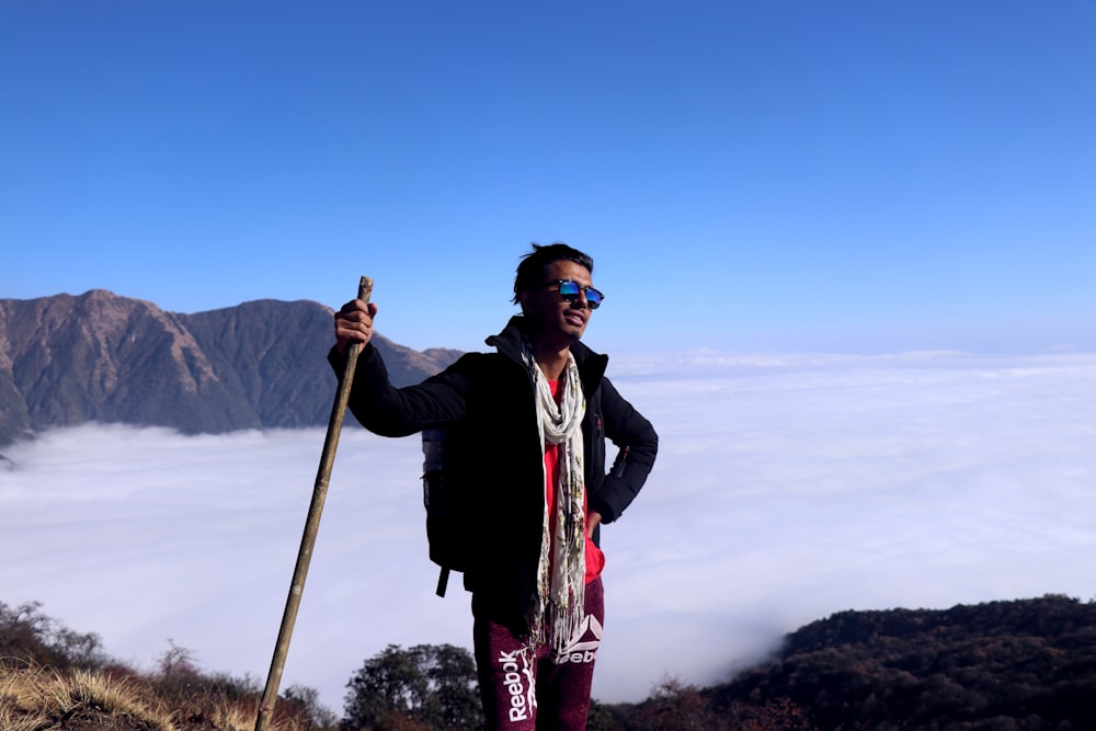 man in black jacket and red pants standing on brown rock during daytime