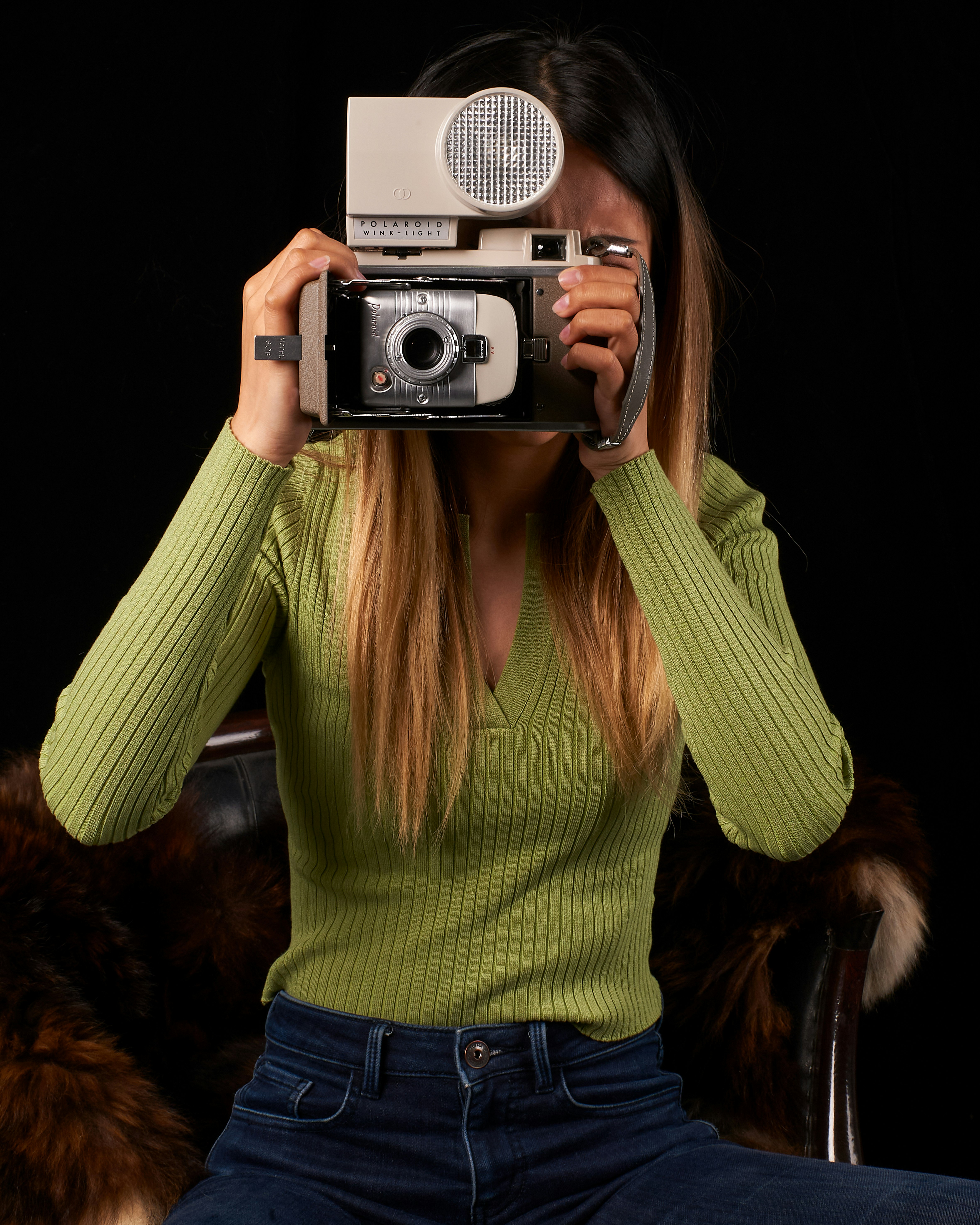woman in green sweater holding silver and black camera