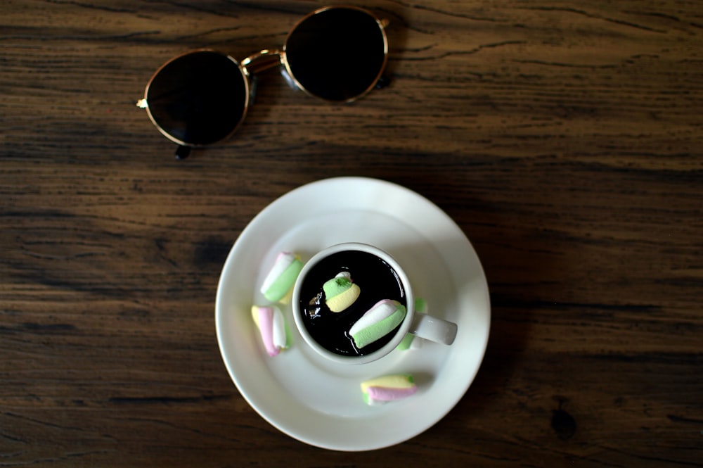 black sunglasses beside white ceramic bowl with sliced cucumber