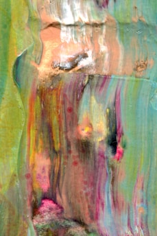 An abstract painting with flowing colors including green, pink, orange, and blue, creating a sense of movement and depth. The texture appears to be layered with brushstrokes and blending, evoking a fluid, almost watery appearance.