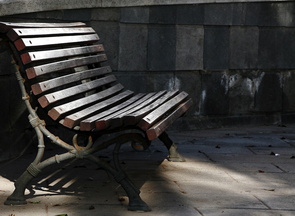 brown wooden bench near gray concrete wall