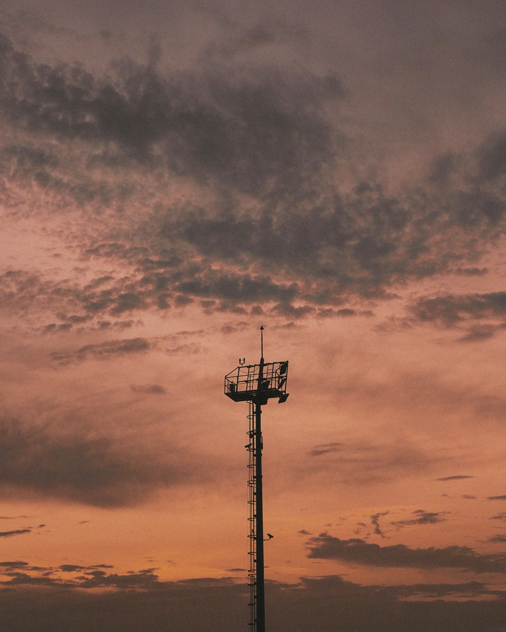 silhouette of post under cloudy sky during sunset
