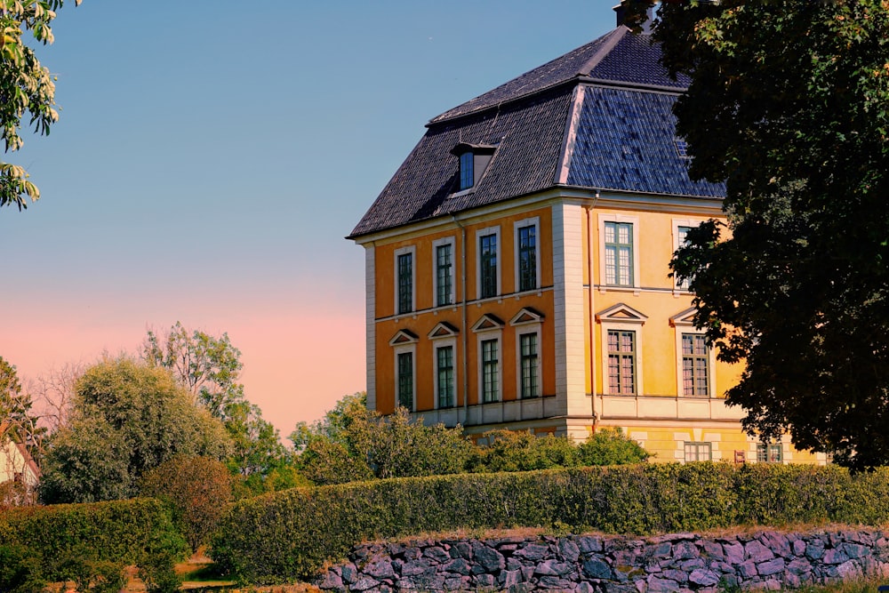 Braunes und schwarzes Betonhaus in der Nähe von grünen Bäumen unter blauem Himmel tagsüber