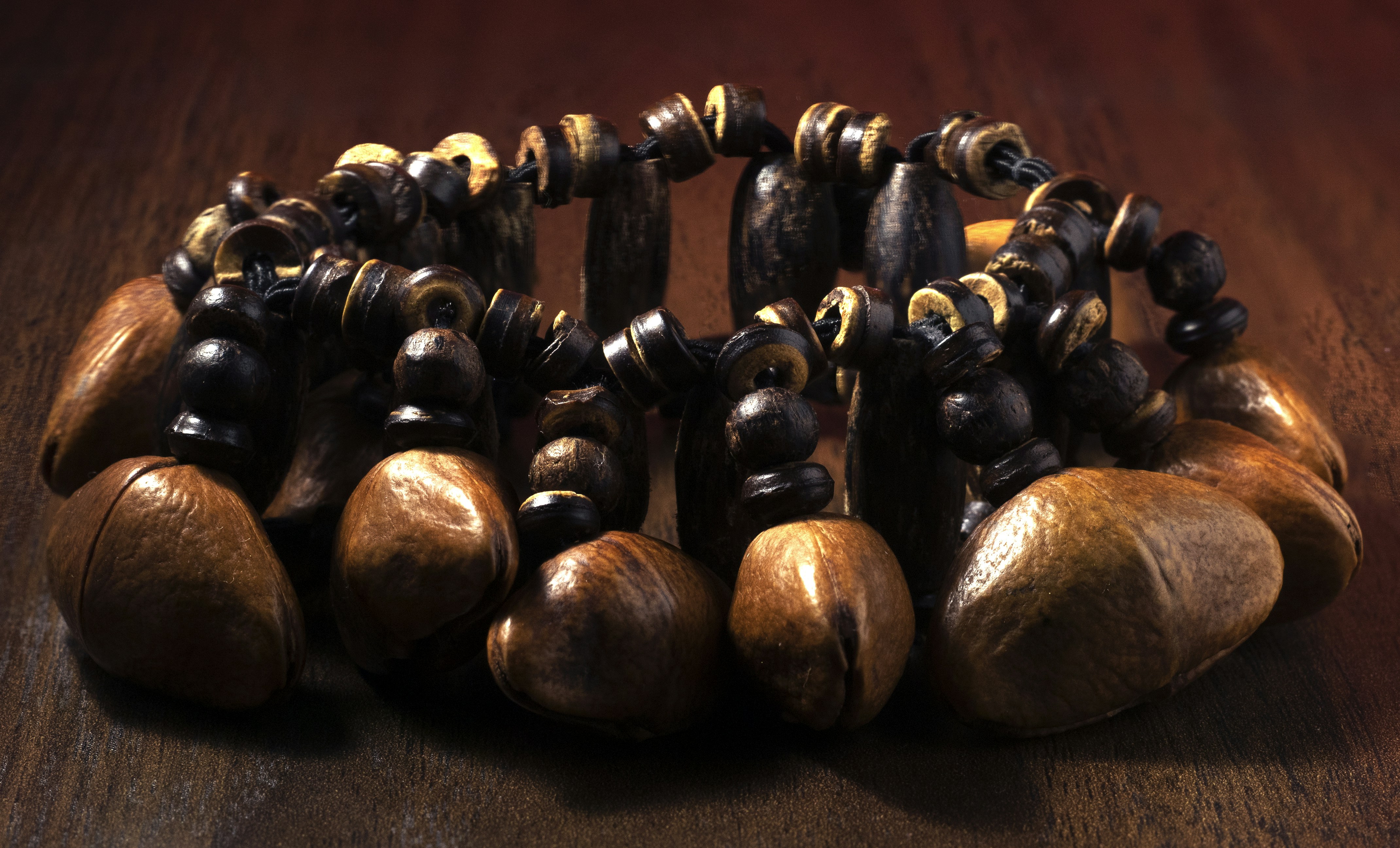 Collection of brown natural seed beads on warm wooden surface, soft natural daylight, earthy organic texture
