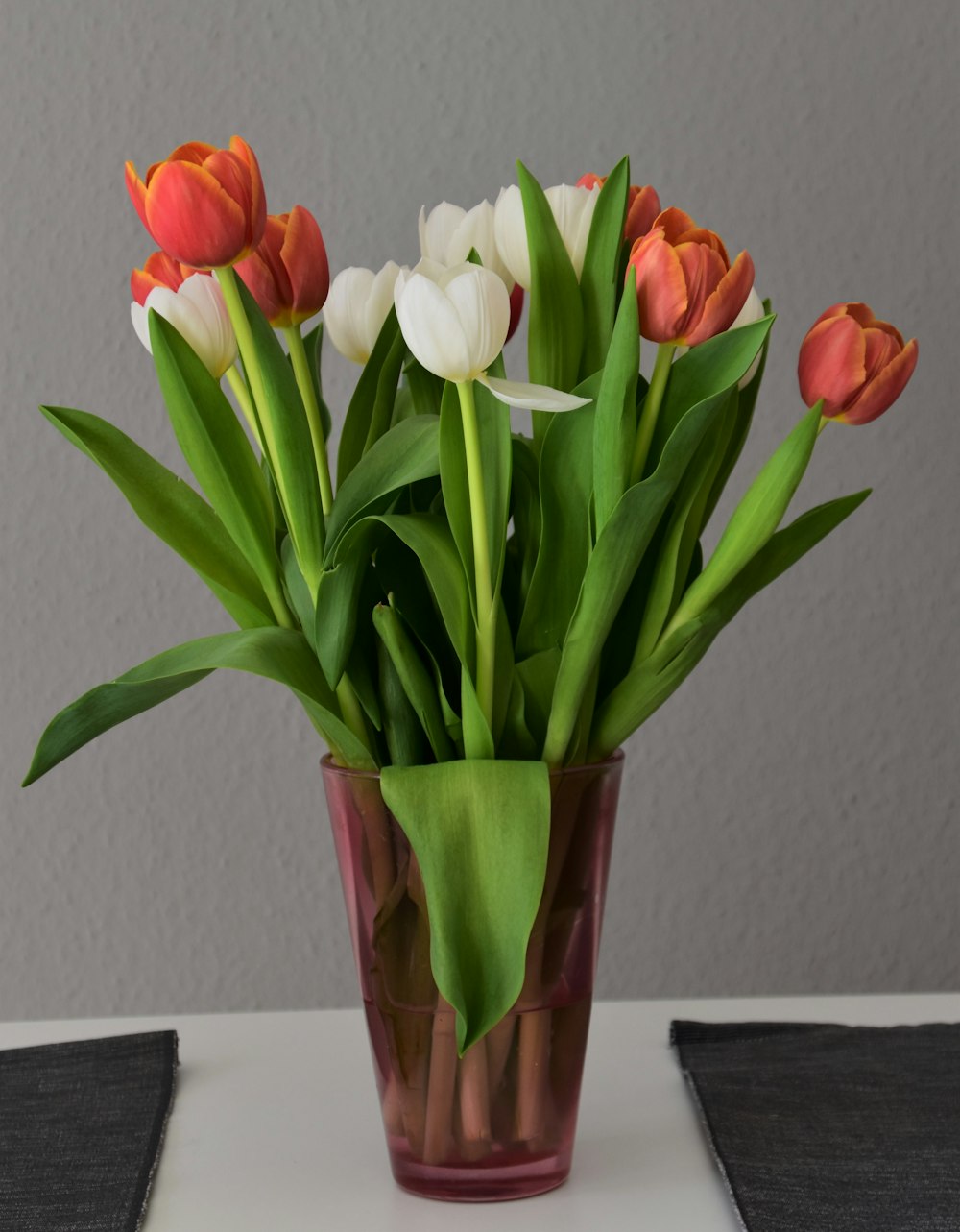 red and white tulips in green glass vase