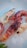 Several raw prawns are displayed on a bed of crushed ice, highlighting their fresh, glossy shells with shades of pink and white. The setting suggests a seafood market or preparation for a gourmet meal.