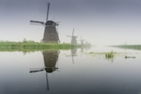 windmill near lake during foggy weather