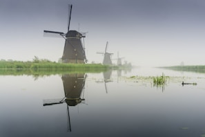 windmill near lake during foggy weather