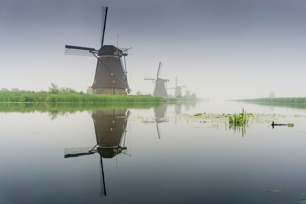 windmill near lake during foggy weather