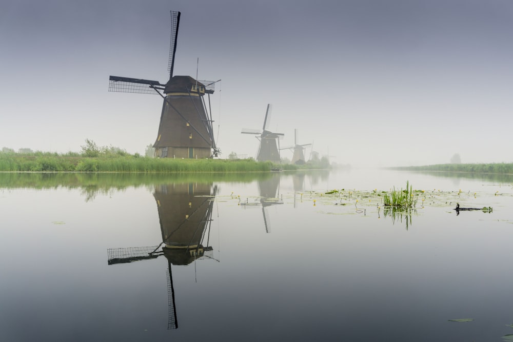 windmill near lake during foggy weather
