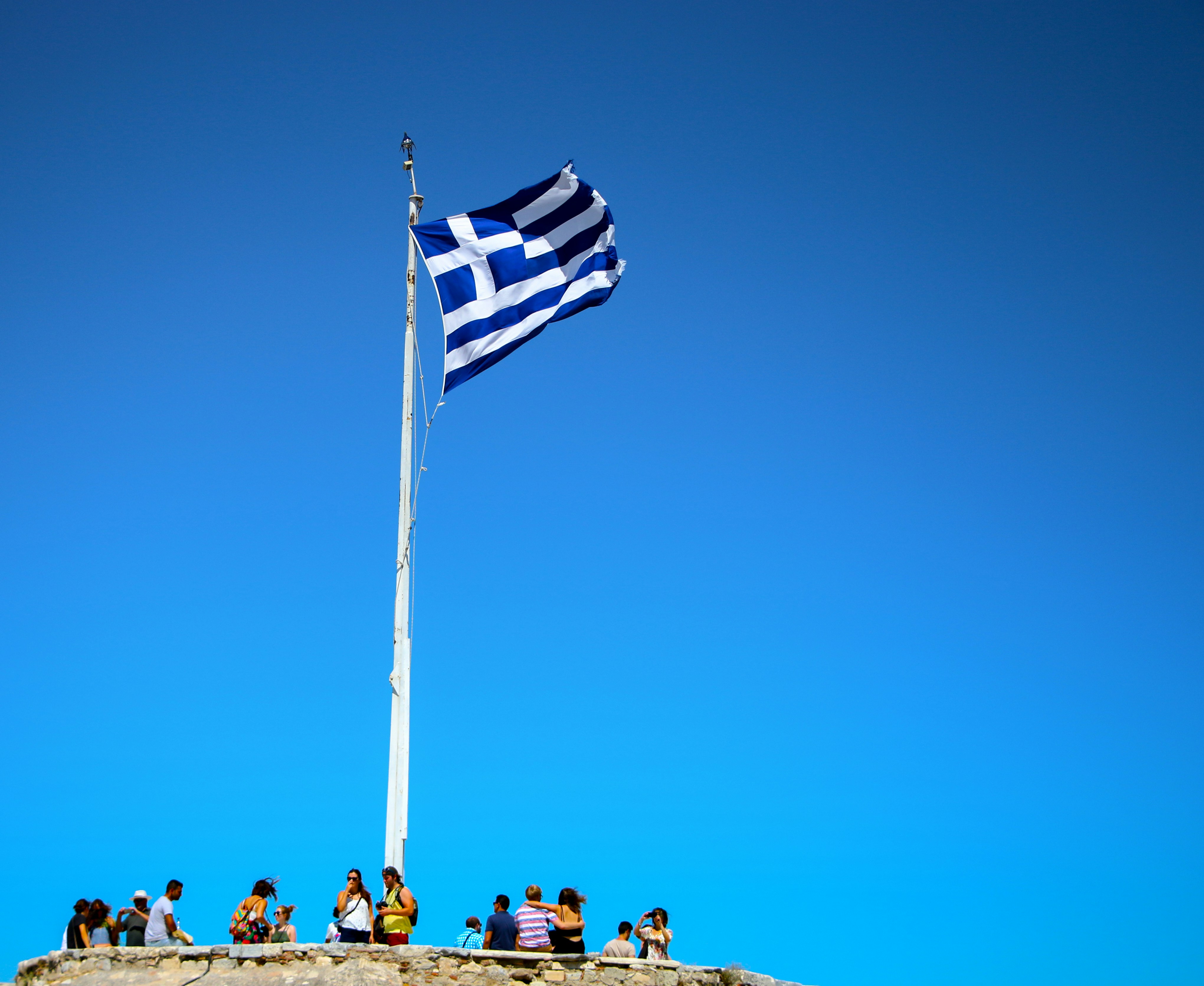 blue and white striped flag on pole during daytime, "Hellenic Flag at Acropolis" - Athens, Greece.