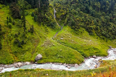 A lush green valley with a winding river cutting through the terrain.