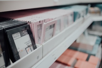A shelf filled with neatly arranged picture frames in various colors, including black, pink, and blue. The frames are of similar size and are packed closely together, suggesting a retail display.
