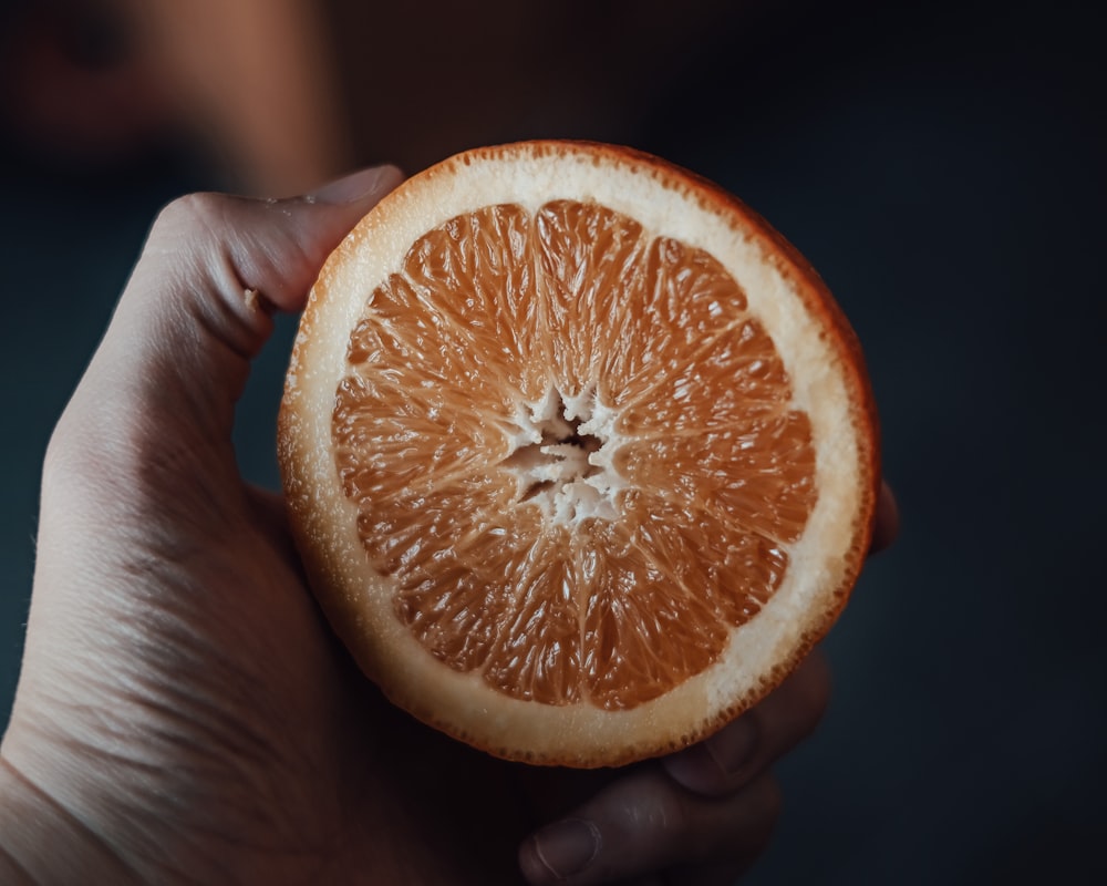 person holding orange citrus fruit