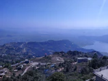 A panoramic view of the Atlas Mountains with paragliders dotting the sky and vibrant green valleys below.