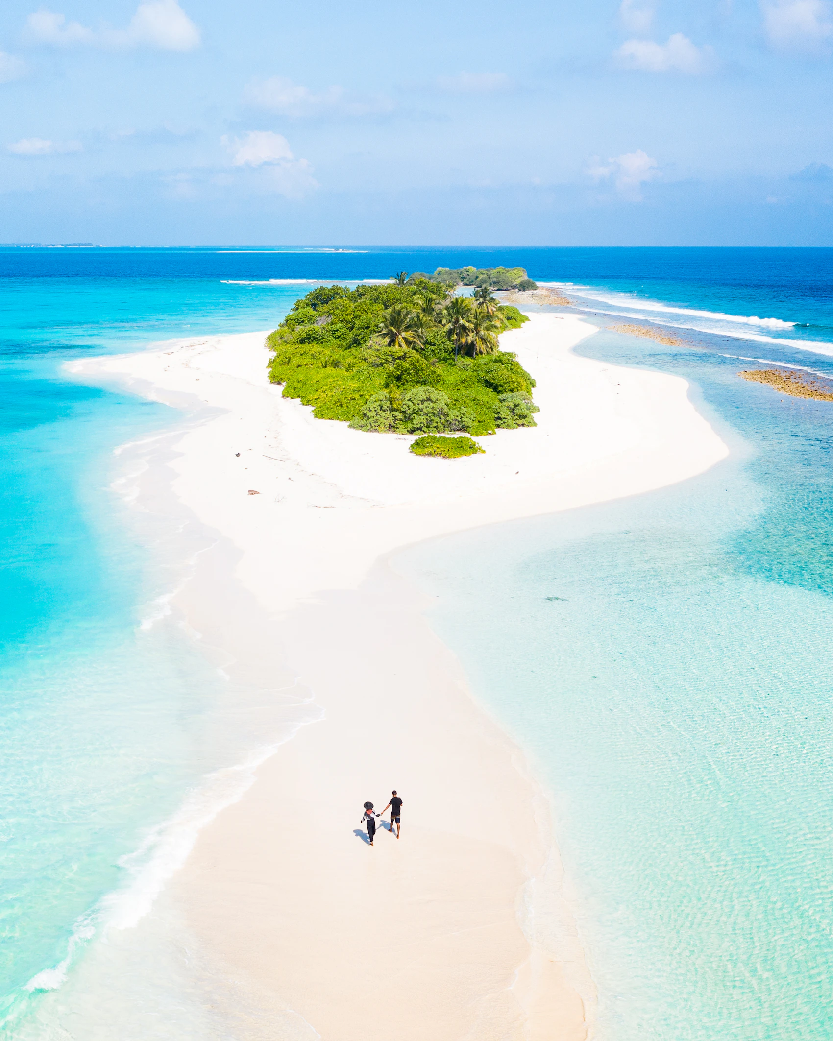 People walking along the shore of a small Maldives island