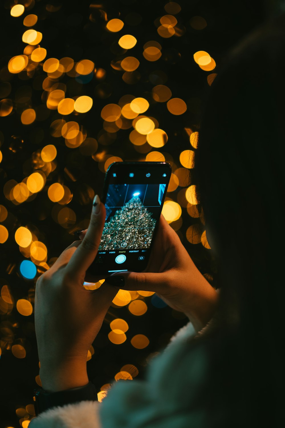 person holding black iphone 5 taking photo of yellow bokeh lights