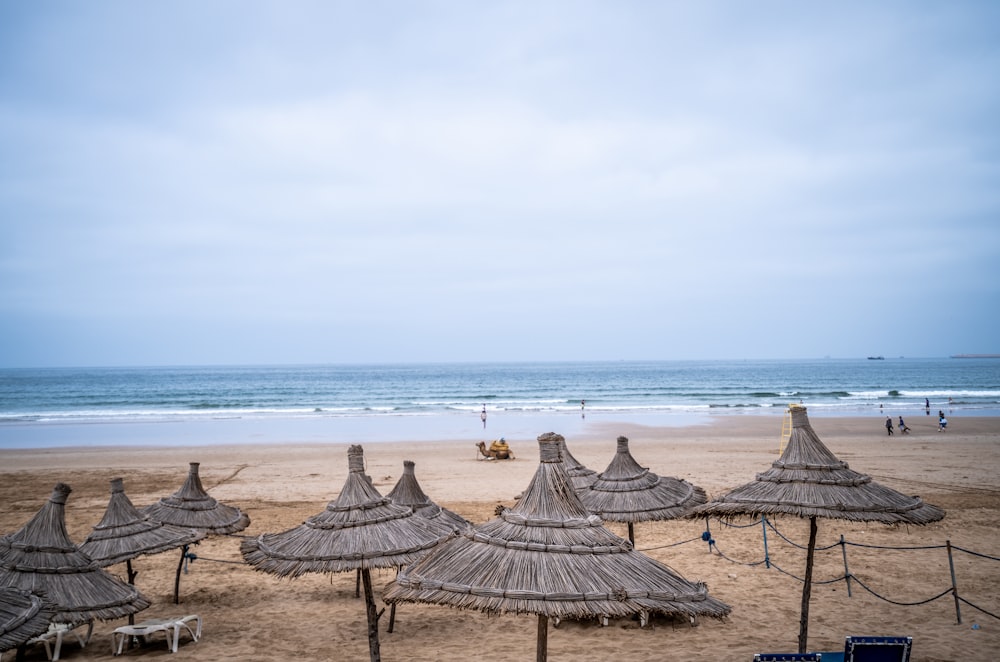 brown wooden beach umbrellas on beach during daytime