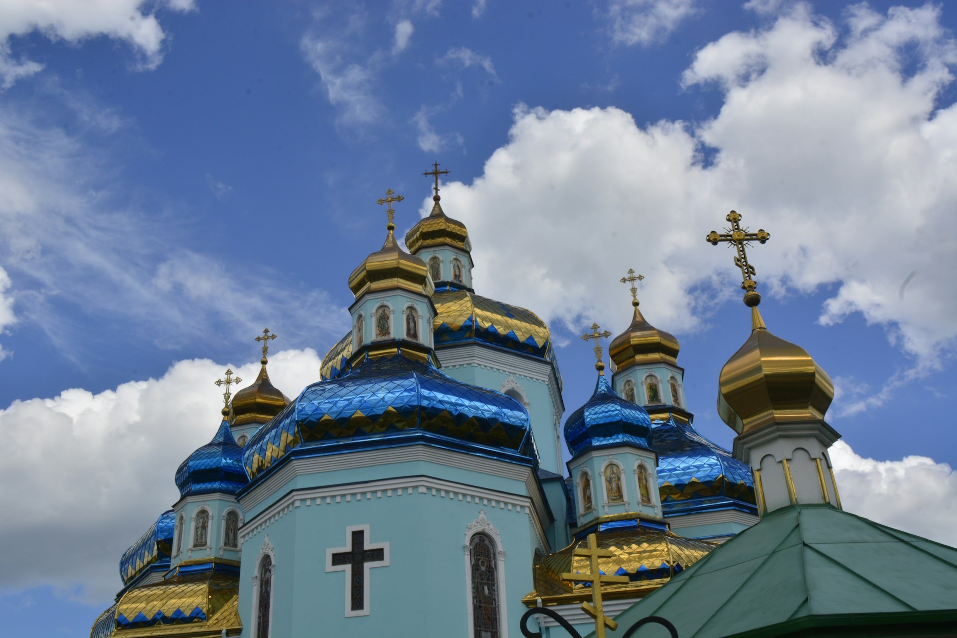 The iconic domes of the Church of the Holy Sepulcher framed by a clear blue sky, bustling with tourists and locals.