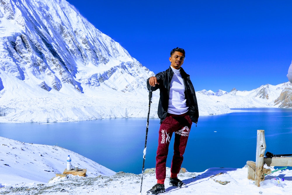 man in black jacket and blue pants standing on snow covered ground during daytime