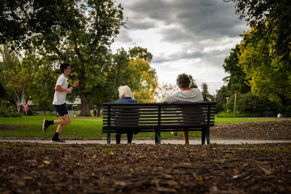 2 women standing beside black wooden bench under white clouds during daytime