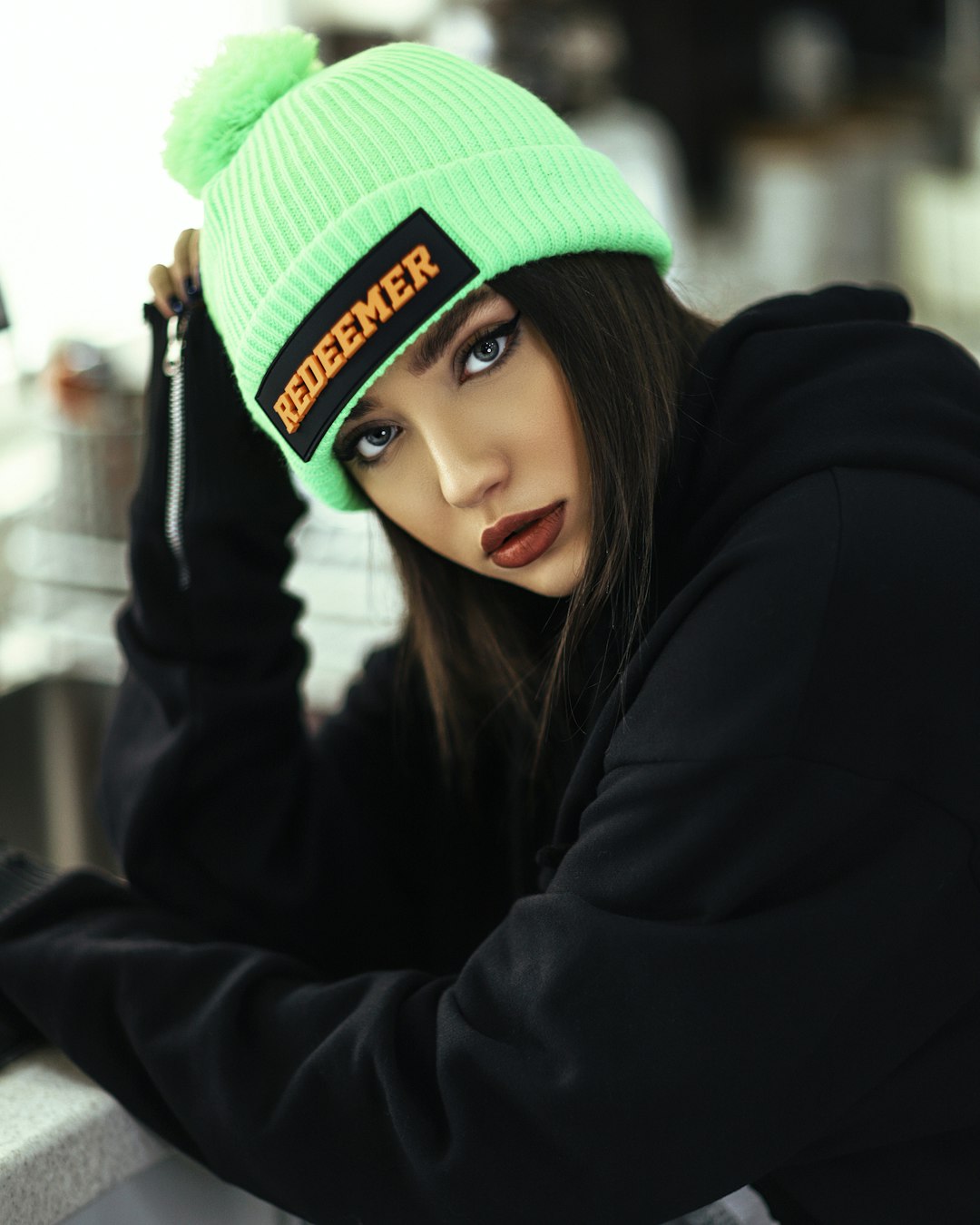 woman in black jacket wearing green knit cap