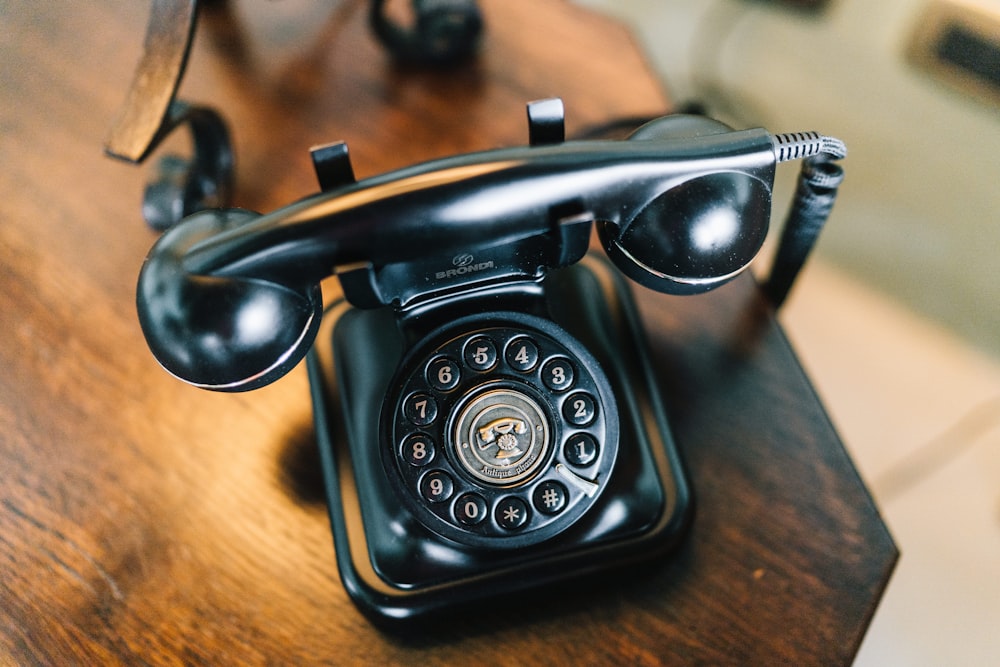 black rotary phone on brown wooden table