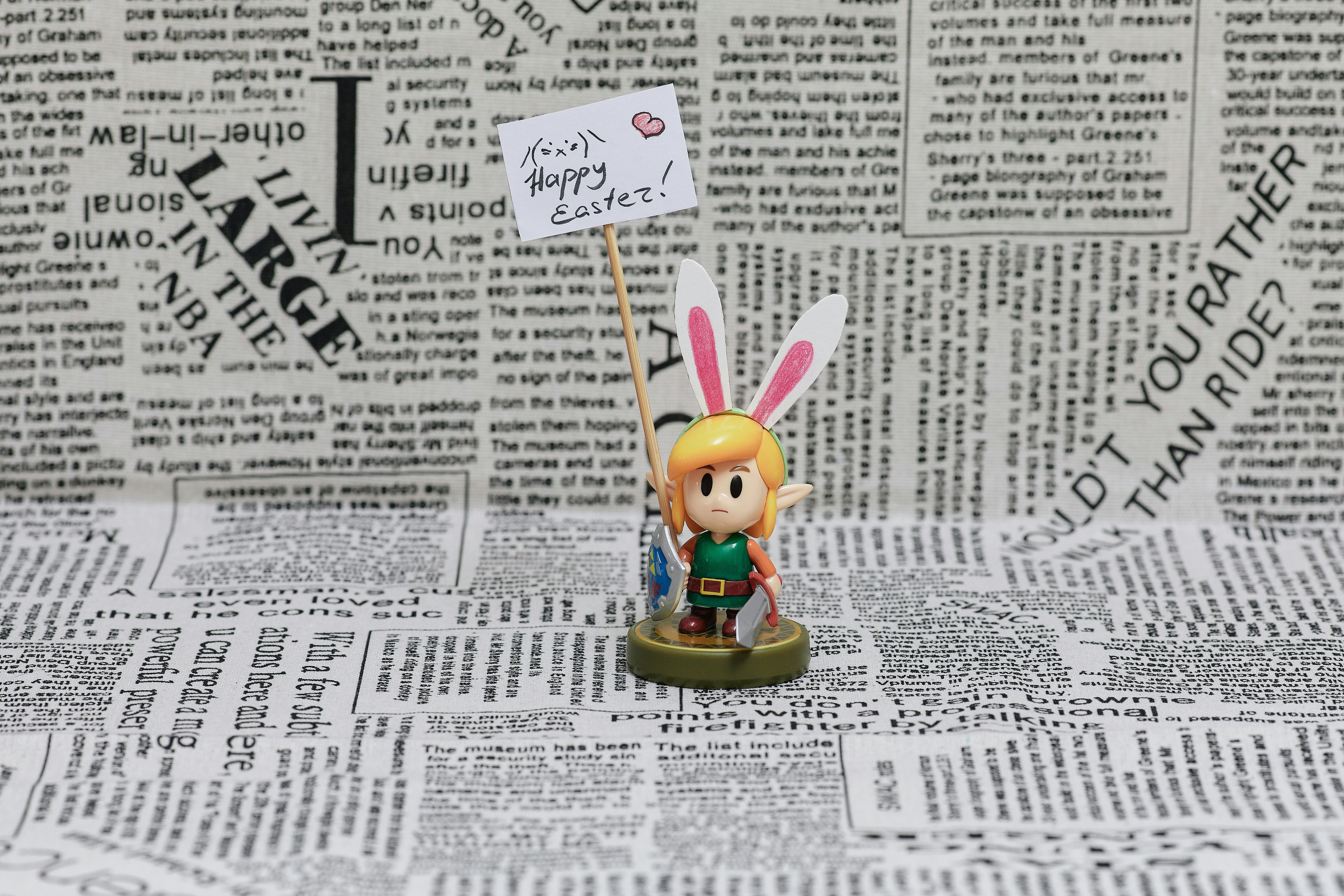 The character from the game (Link) on a newspaper background with a tablet in his hands. The plaque says \