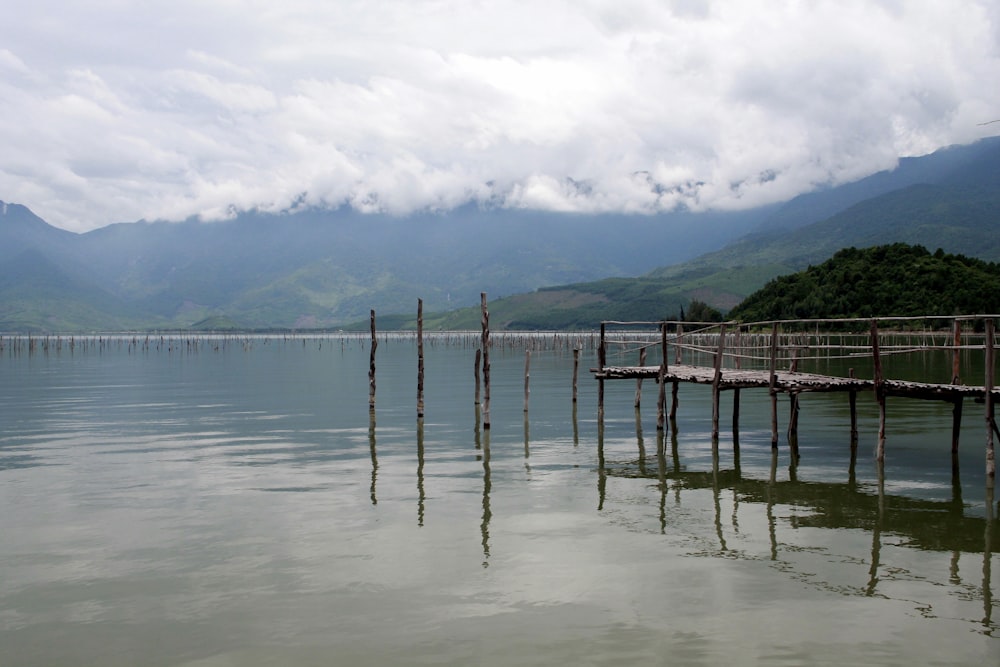 brown wooden dock on sea under white clouds during daytime