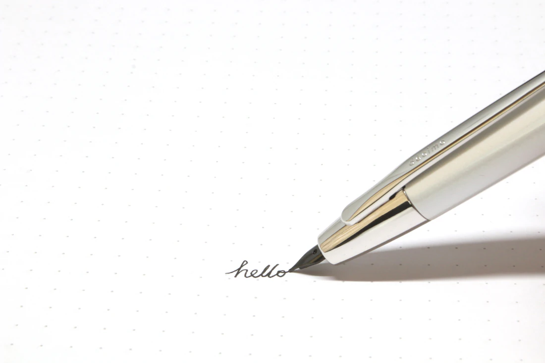 A silver click pen on white paper
