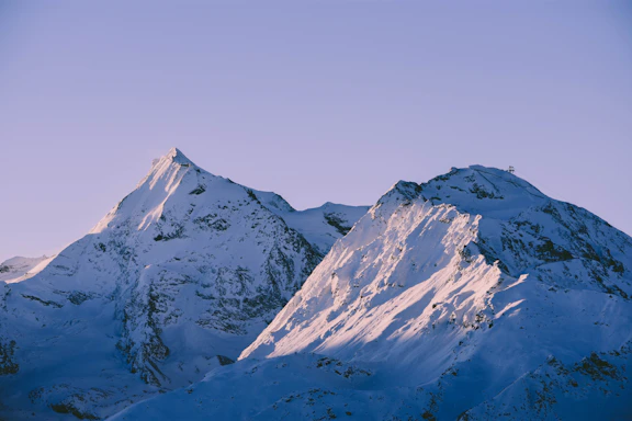 A serene close-up of icy mountain peaks glowing softly under a pastel sunset sky.