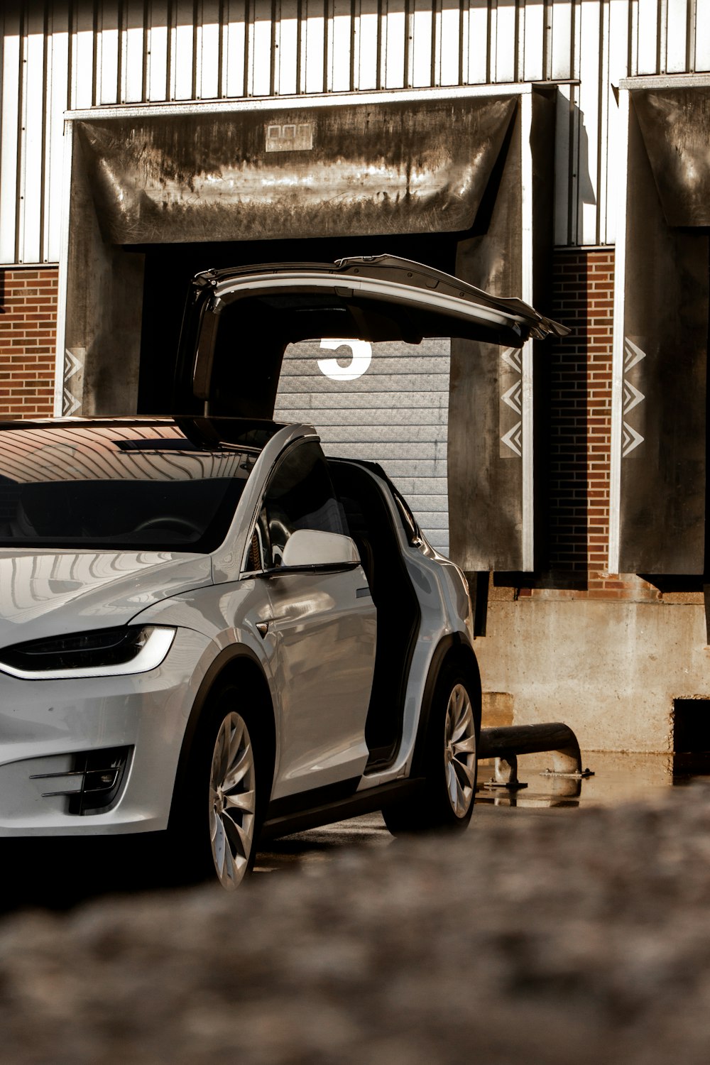 silver sedan parked beside brown brick wall