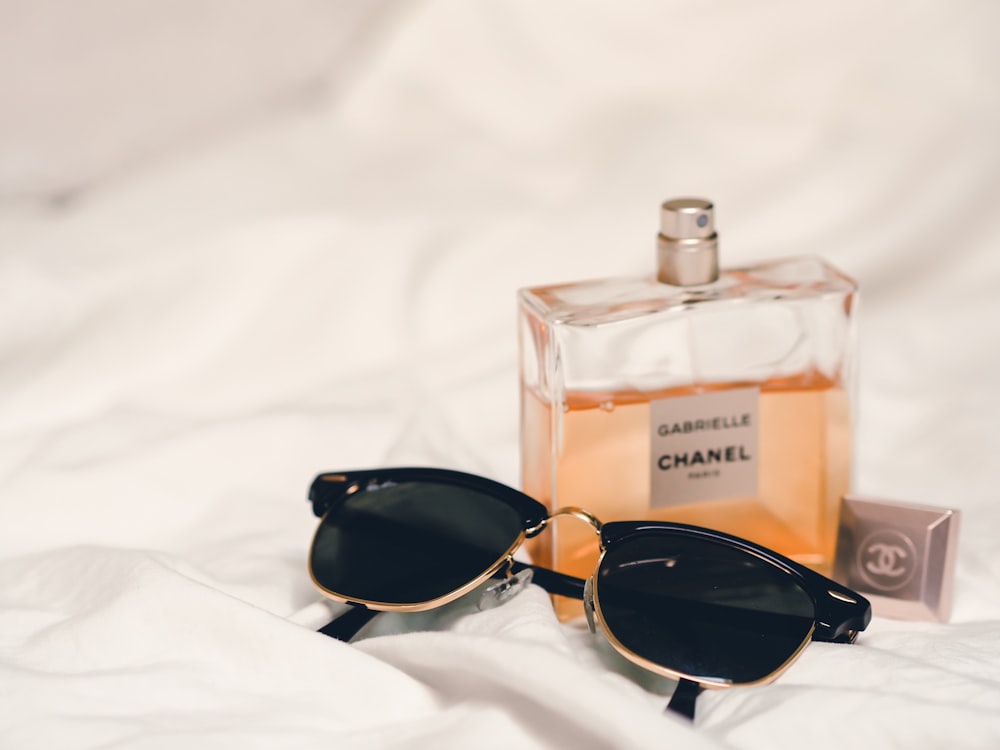 black sunglasses beside perfume bottle