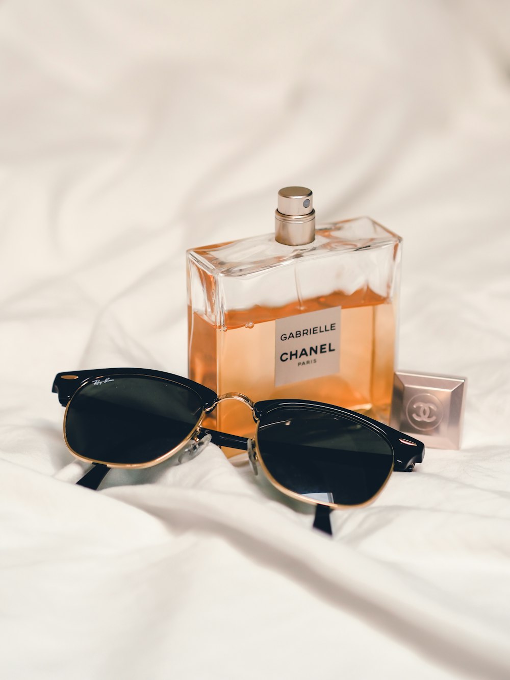 black sunglasses beside perfume bottle