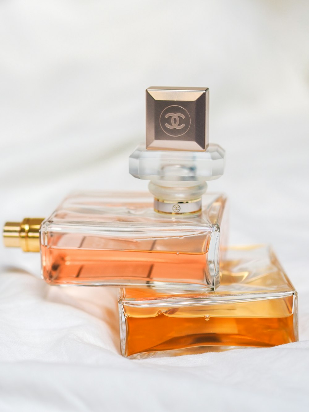 clear glass perfume bottle on white textile