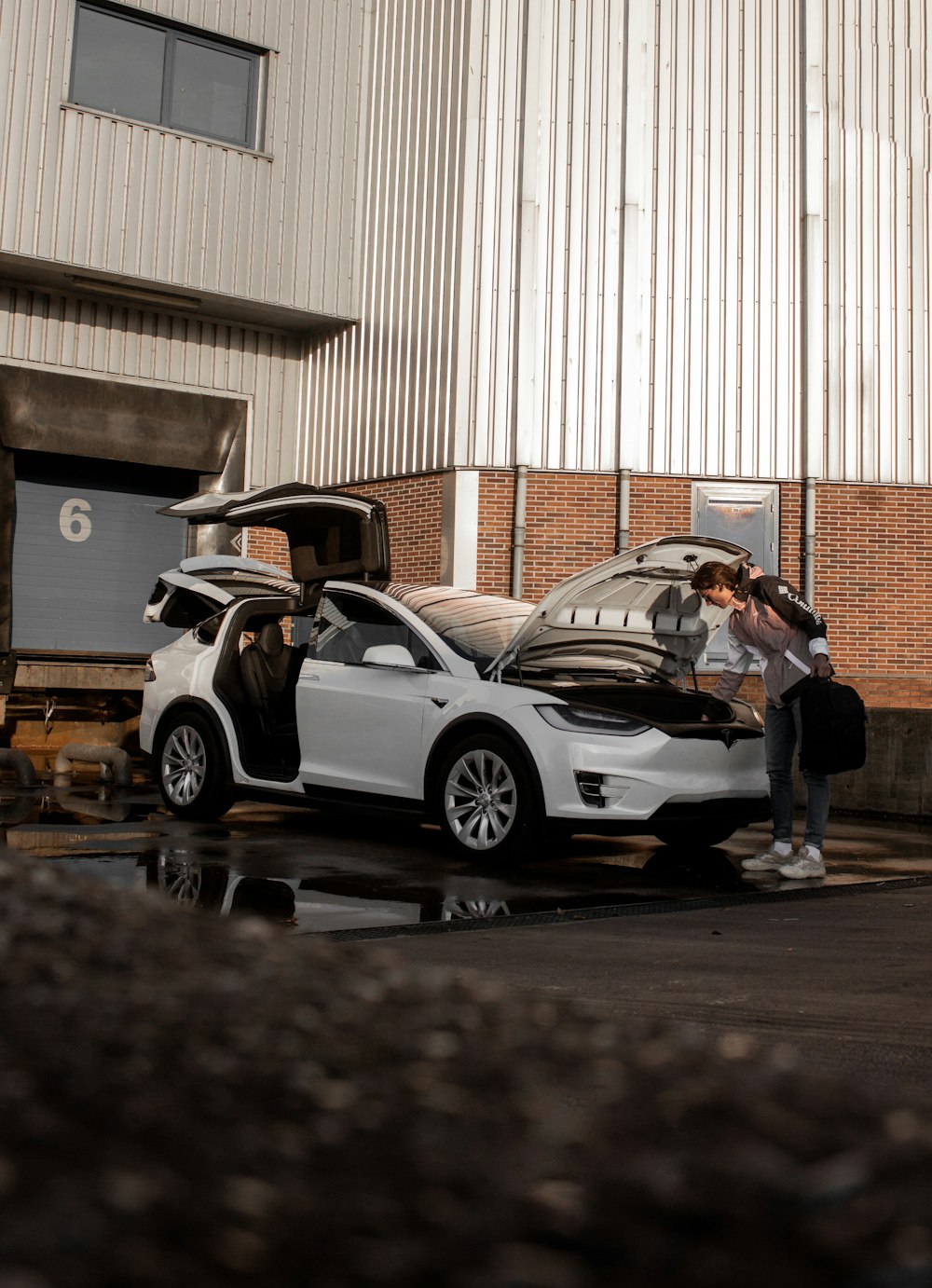 man in black jacket and black pants standing beside white car