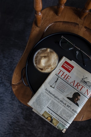 A serene morning scene with a newspaper and coffee cup on a wooden table.
