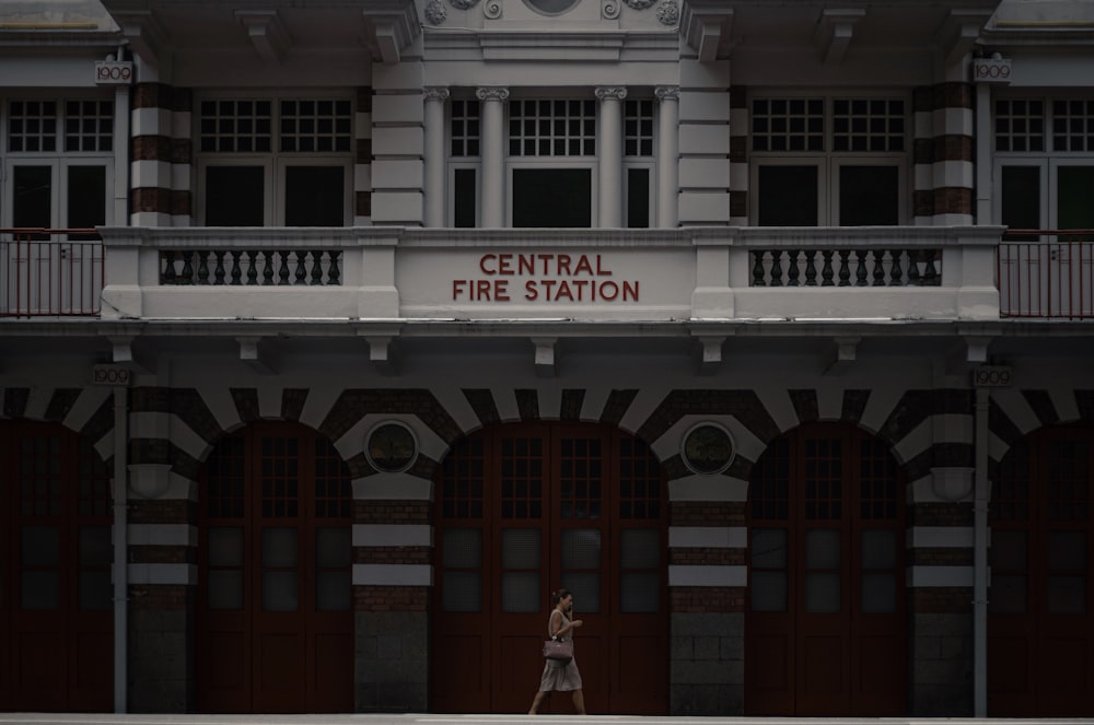 Mujer en vestido blanco de pie frente a un edificio de hormigón blanco