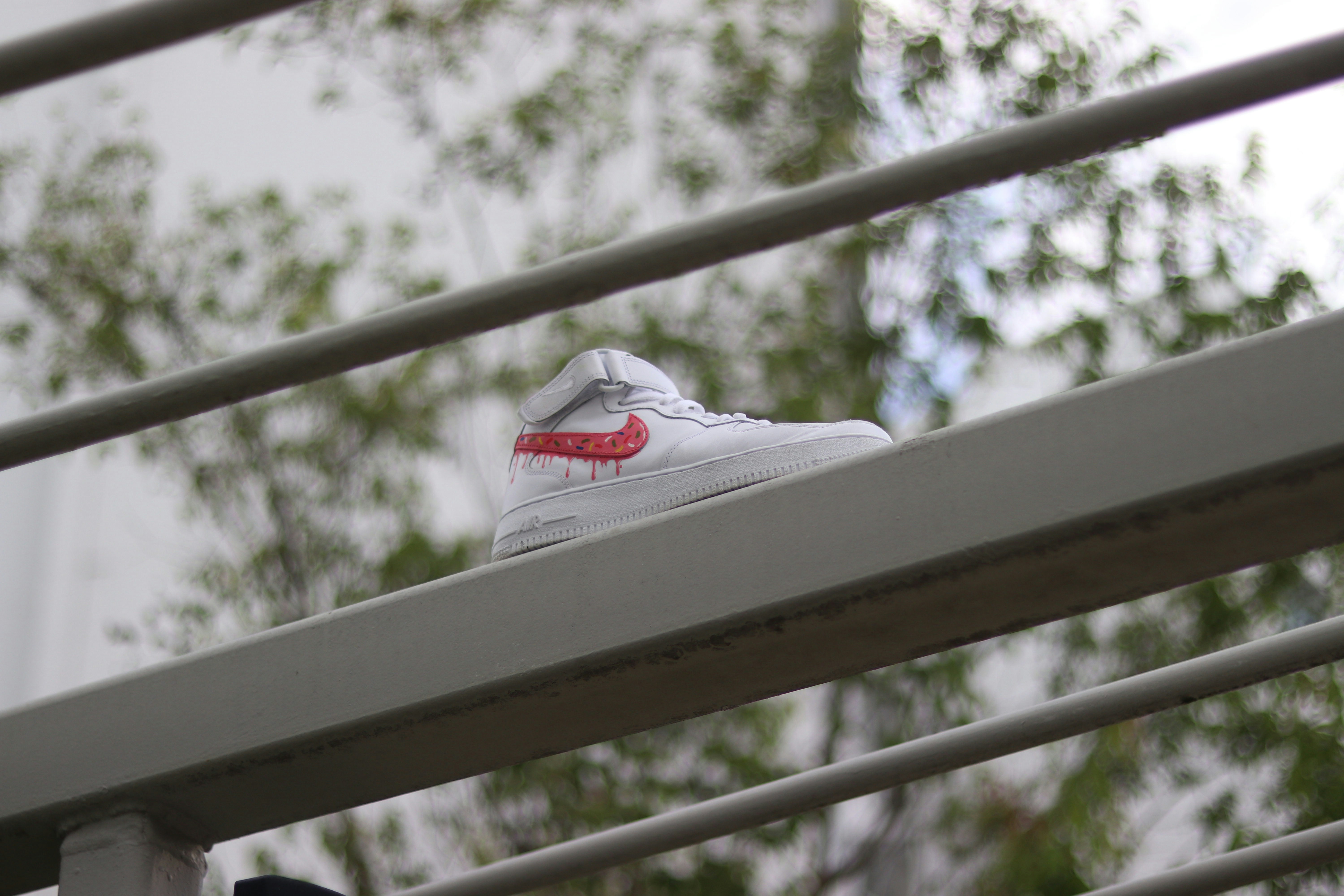 white and red nike shoe on white wooden fence