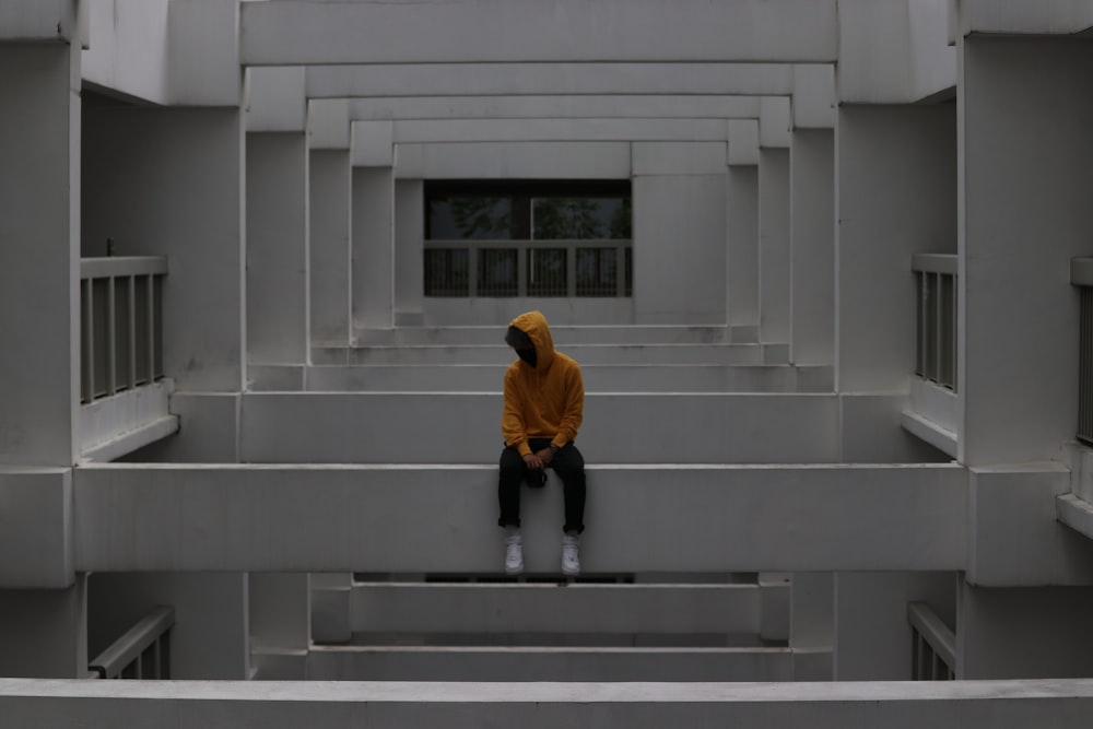 man in yellow hoodie walking on gray concrete stairs