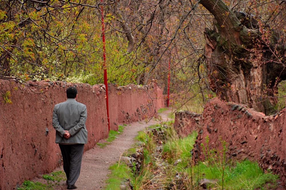 man in gray jacket walking on pathway