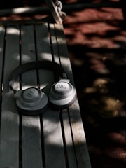 white sony headphones on black wooden bench