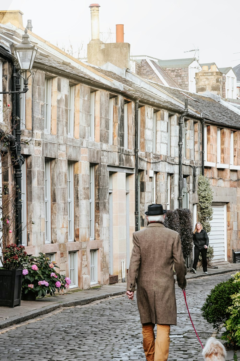 homme en manteau gris marchant sur le trottoir pendant la journée